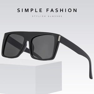 Oversized black frame sunglasses with gray lenses and silver metal details on a white block