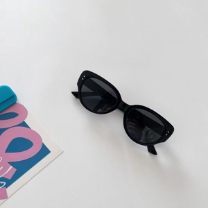 Detailed view of kids vintage black sunglasses with silver dot accents and dark lenses