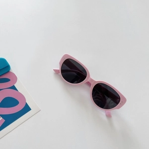 Detail view of pink cat-eye sunglasses with dark lenses on a white background