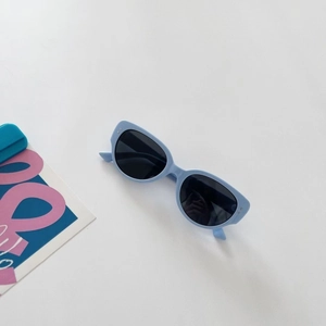 Detail of baby blue cat-eye kids sunglasses with dark lenses and silver dot accents