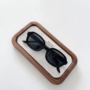 Close-up of kids vintage oval sunglasses with matte black frames on a linen tray