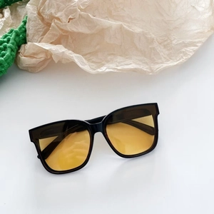 Detail der quadratischen schwarzen Kinder-Sonnenbrille mit stilvollen gelben Gläsern
