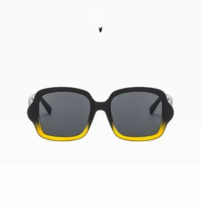 Détail de lunettes de soleil carrées avec monture dégradée du noir vers le jaune vif