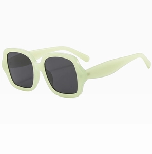Détail de lunettes de soleil carrées vert menthe avec verres gris foncé et monture translucide