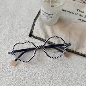 Detail of kids' black and white checkerboard glasses with asymmetric heart-round frames