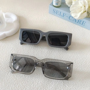 Two pairs of trendy rectangular sunglasses in solid and transparent grey on white decor
