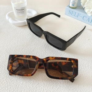 Flat lay of retro rectangle sunglasses in black and tortoiseshell on a textured surface