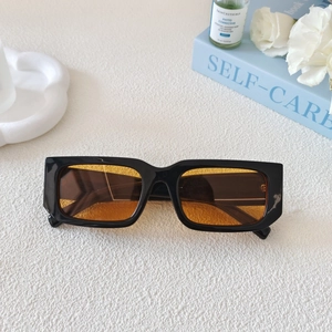 Close-up of retro rectangular sunglasses with black frames and orange tinted lenses
