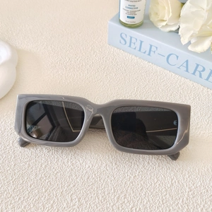 Detail of retro rectangle sunglasses with grey frames and black lenses on a styled desk