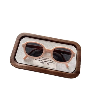 Foldable vintage oval sunglasses for kids with pink frames and dark lenses on a tray