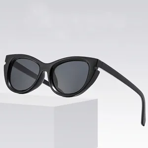 Classic black cat-eye sunglasses with dark grey lenses on a white geometric stand