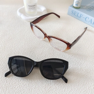 Detail of tortoise shell oval frame and black cat eye sunglasses on textured fabric
