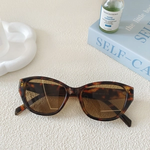 Detail of tortoiseshell cat-eye sunglasses with brown lenses on a decorative background