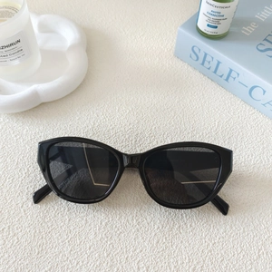 Close-up of retro black cat-eye sunglasses on a white tray with lifestyle decor items
