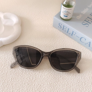 Chic cat-eye sunglasses with translucent grey frames and dark lenses on a neutral surface
