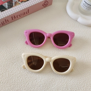 Détail de lunettes de soleil œil-de-chat rétro pour enfants en rose et beige sur blanc