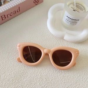 Vue détaillée de lunettes de soleil œil de chat roses pour enfants sur une table blanche