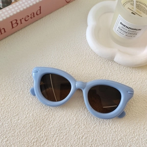 Détail des lunettes de soleil pour enfants bleu clair avec verres foncés sur une table blanche