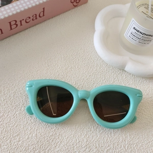 Gros plan de lunettes de soleil œil de chat vert menthe pour enfant sur surface déco