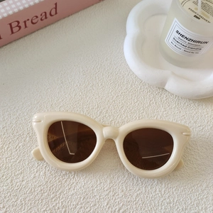 Détail de lunettes de soleil enfant œil-de-chat crème avec design de branche ondulée