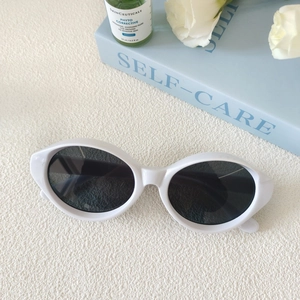 Vue détaillée des lunettes de soleil ovales blanches oeil de chat sur un décor de boîte cadeau