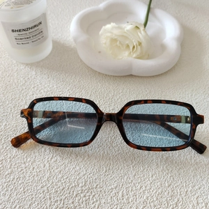 Gros plan de lunettes de soleil rectangulaires en écaille avec des verres bleu clair