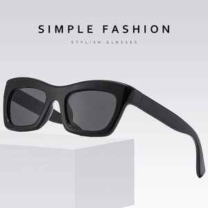 Lunettes de soleil œil-de-chat noires à monture épaisse avec verres gris sur support