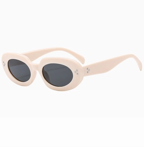 Detailed view of oval cream beige sunglasses with decorative silver rivets and dark lenses