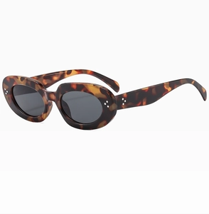 Detail view of oval tortoise shell sunglasses featuring triple metal rivet accents