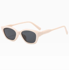 Detail view of oval cat-eye sunglasses with cream frames and dark UV protection lenses