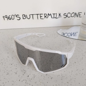 Detail of white cycling glasses with dark lenses and ventilated frame for kids
