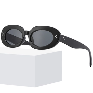 Retro oval black sunglasses with silver rivet accents on a minimalist white platform