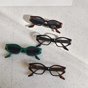 Kids cat-eye UV400 sunglasses in green, black, and tortoiseshell on a tile background