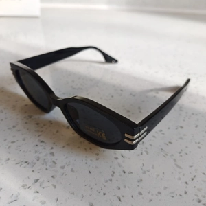 Detail of black sunglasses with UV400 protection label and silver hinge accents