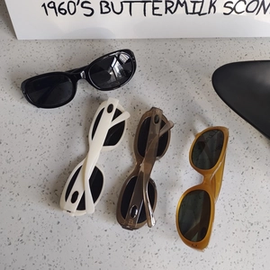 Retro oval sunglasses in black cream grey and amber colors on a stone background