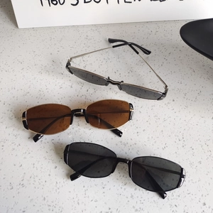 Three retro narrow cat-eye sunglasses with tea brown and black lenses on white stone