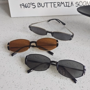 Three pairs of vintage cat-eye sunglasses in black and brown on a stone surface