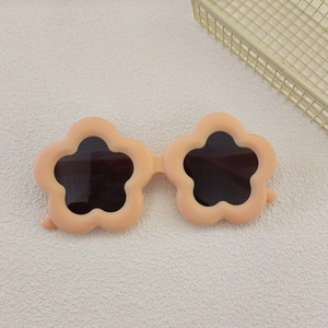 Macro view of peach flower-shaped kids sunglasses with matte frame and dark round lenses