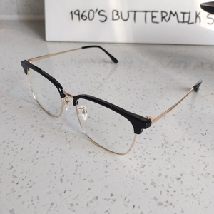 Detail view of semi-rimless glasses with black and gold frame on a textured surface
