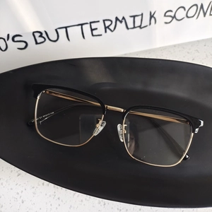Detail view of half-rim glasses with black and gold metal frames and size engraving