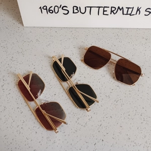 Close-up of geometric aviator sunglasses in brown black and burgundy with gold metal frames