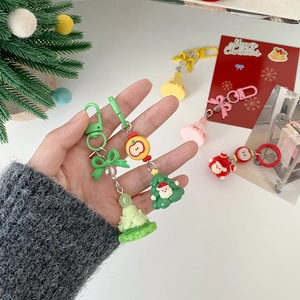 Cute Santa Claus and green bow resin keychain set held as a festive holiday gift