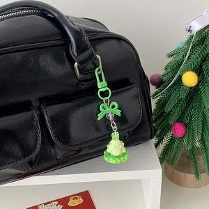 Green Christmas tree bag charm with bow on black leather handbag background