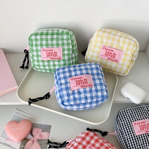 Detail of colorful gingham quilted mini makeup bags with zippers and pink fabric labels