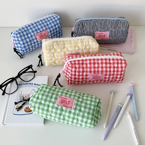 Quilted heart pattern pencil case set in five colors with stationery on a desk