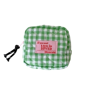 Quilted green and white checkered pouch with pink label for cosmetics and lipstick