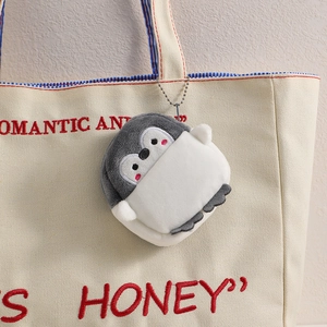 Cartoon penguin plush coin purse and keychain hanging on a canvas bag with silver chain