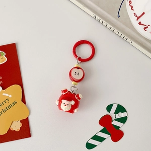 Detail view of Santa Claus and apple charms on a red Christmas keychain with festive cards