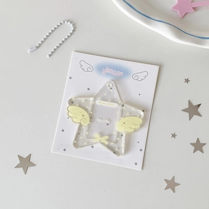 Detail of star-shaped acrylic card holder with glitter and wings on a decorative background
