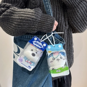 Plush bear doll in milk box transparent carrier bag hanging on a denim backpack